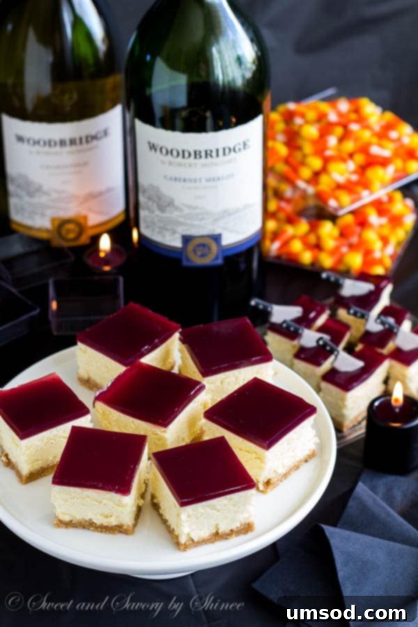 Finished thick, creamy cheesecake bars topped with a vibrant wine gelée, ready to be sliced and served.