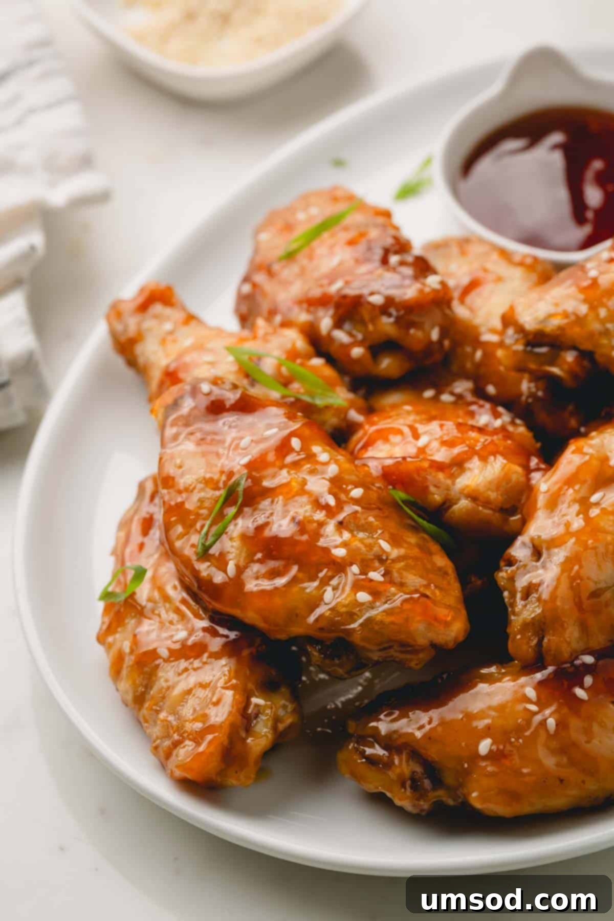 Sticky Teriyaki Chicken Wings 2 A platter of oven baked teriyaki chicken wings topped with fresh green scallions and white sesame seeds, ready to be served.