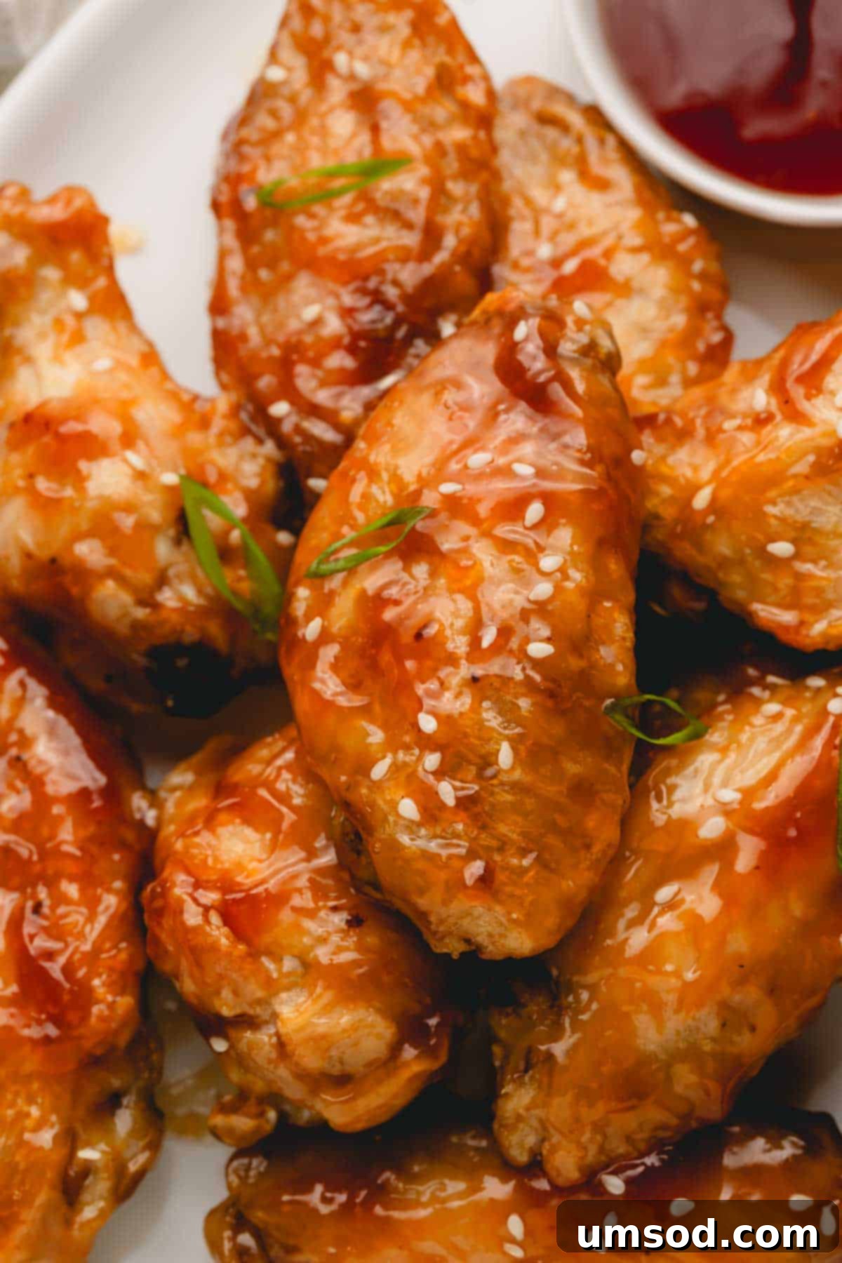 Sticky Teriyaki Chicken Wings 12 A beautifully arranged platter of oven baked teriyaki chicken wings, garnished with fresh scallions and white sesame seeds, ready for serving at a gathering.
