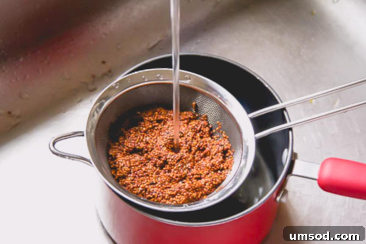 Roasted Brussels Sprout and Warm Quinoa Power Bowl 5 Red quinoa being rinsed in a sifter under running tap water to remove bitterness.