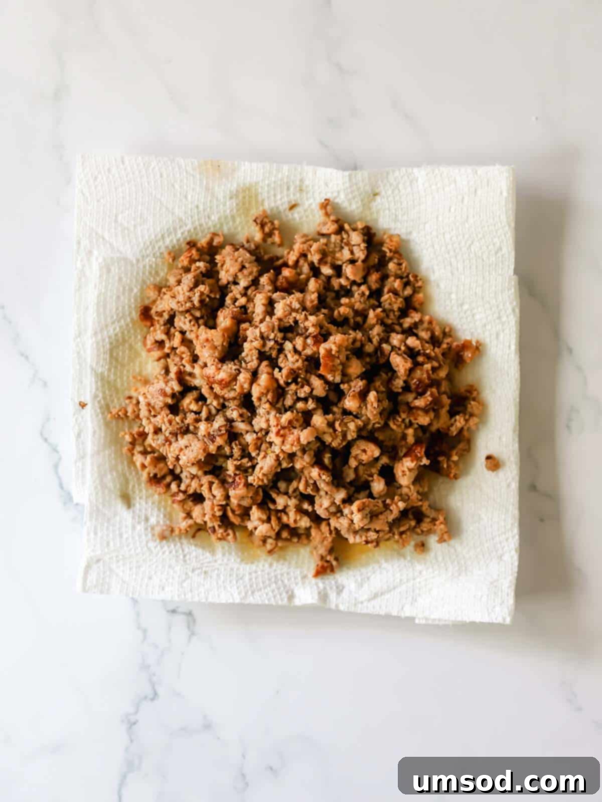 Cooked Italian sausage pieces resting on a paper towel-lined plate to absorb excess fat.