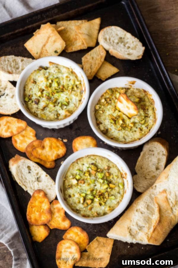 Five Ingredient Pesto Artichoke Dip 3 Creamy baked Pesto Artichoke Dip in a ramekin, ready to be served with crackers.