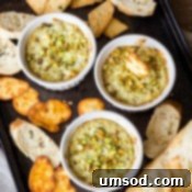 Five Ingredient Pesto Artichoke Dip 8 Close-up of a spoon scooping creamy Pesto Artichoke Dip from a ramekin.