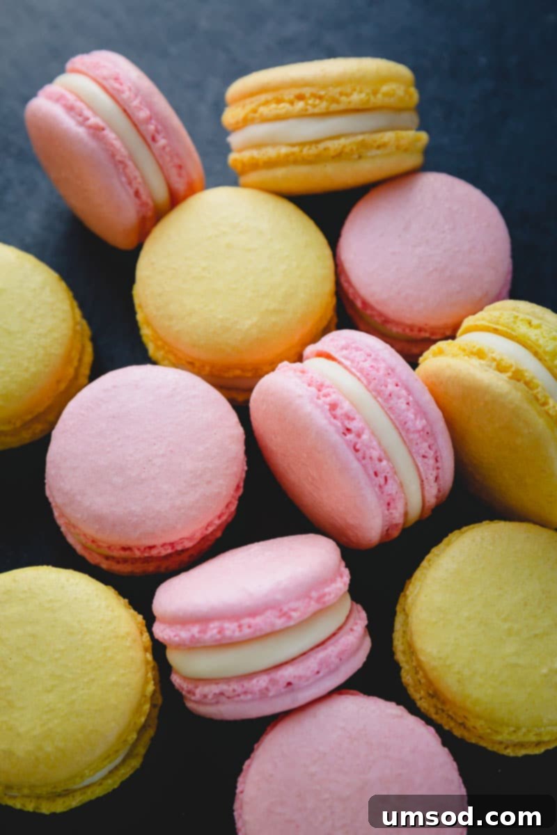 Decoding Macaron Dilemmas 18 Beautifully arranged yellow and pink macarons, filled with a smooth white chocolate ganache, on a dark surface.