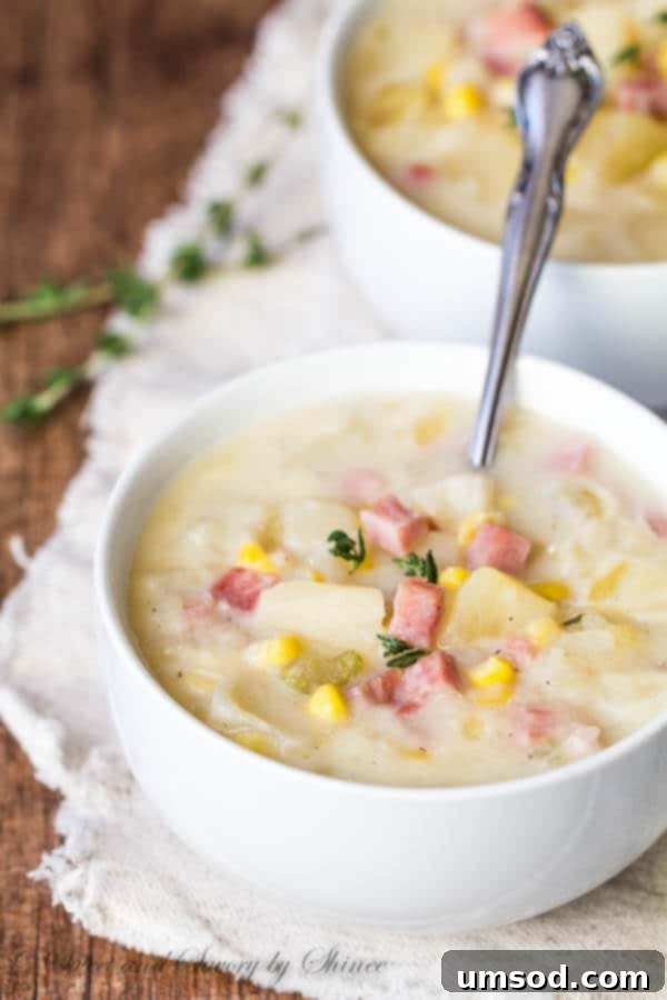 A delicious bowl of slow cooker ham and potato soup with corn, garnished with fresh herbs, ready to be enjoyed.