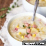 A bowl of slow cooker ham and potato soup with a spoon sticking out.