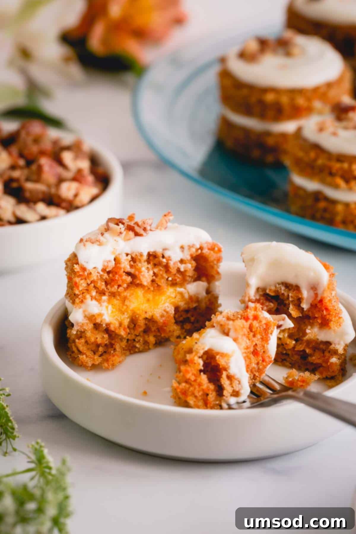 Perfectly Portioned Pecan-Topped Carrot Cakes 11 A mini carrot cake cut in half on a plate, showcasing its layers and texture.