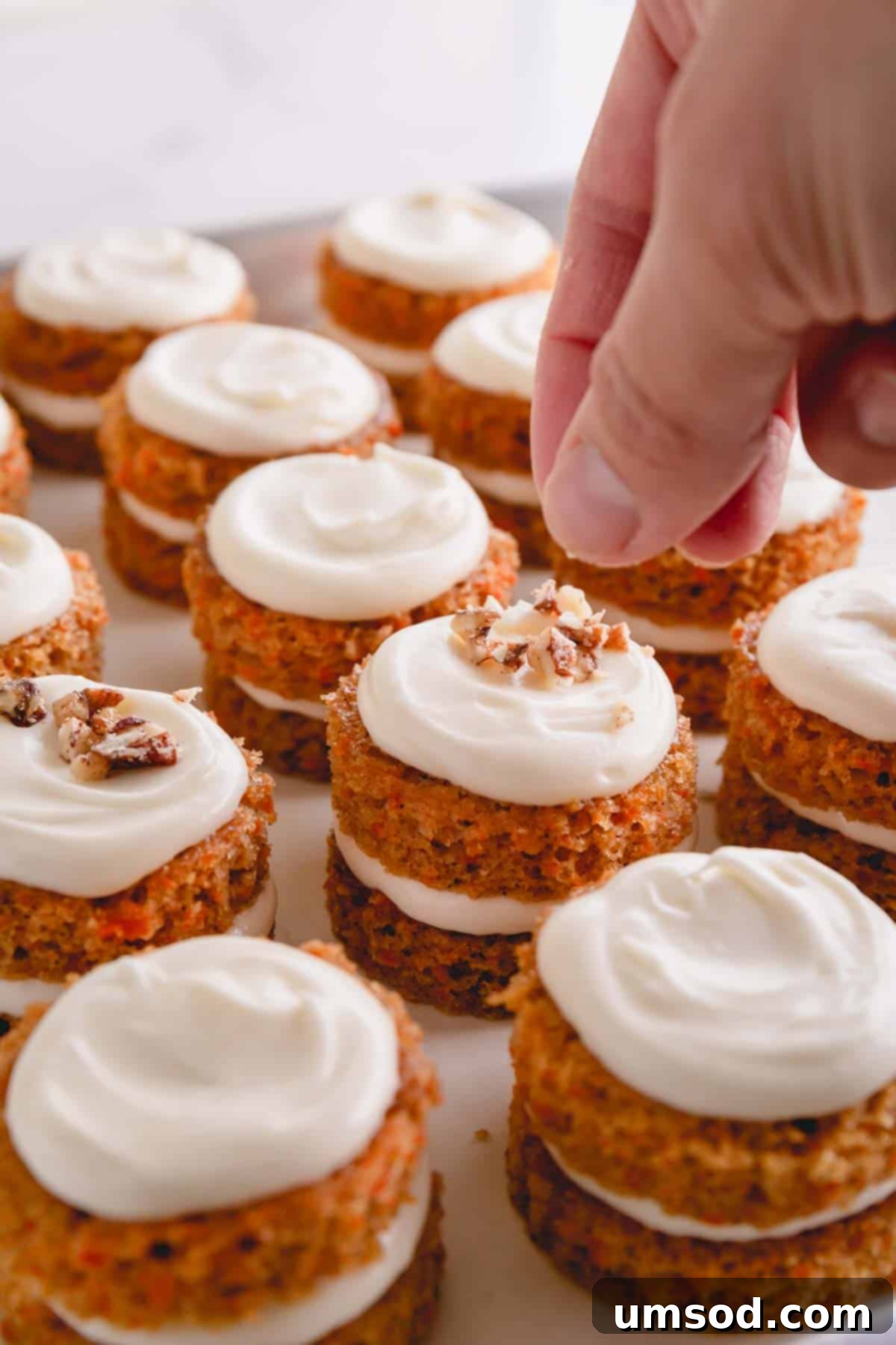 Perfectly Portioned Pecan-Topped Carrot Cakes 10 Hand sprinkling candied pecans on top of assembled mini carrot cakes.