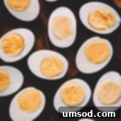 Halved hard-boiled eggs on a cutting board, a reminder of perfect results.