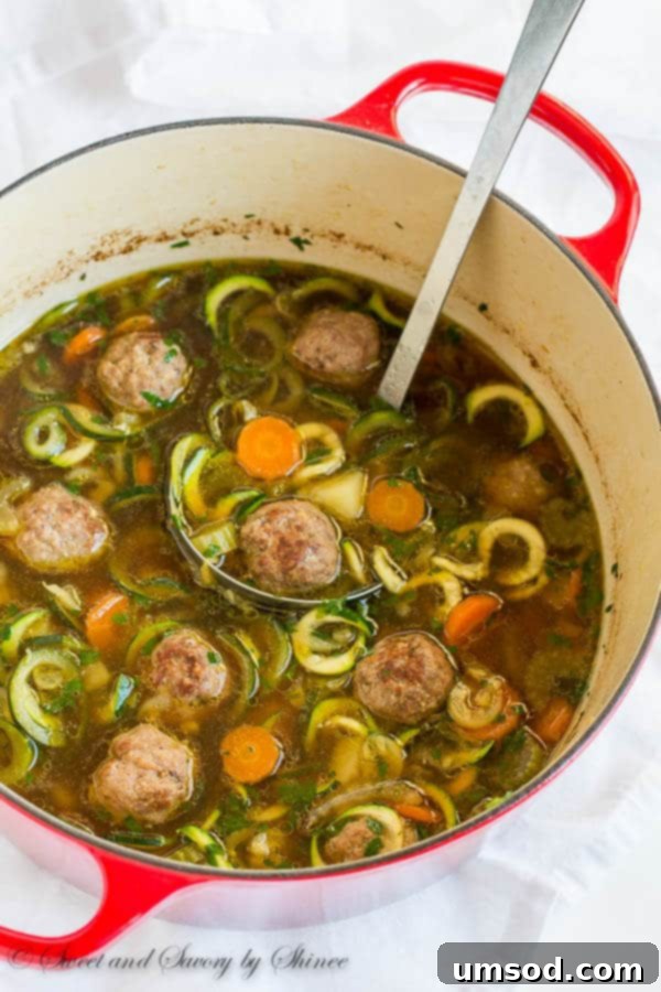 A steaming bowl of hearty vegetable meatball soup, loaded with vibrant vegetables and homemade meatballs, ready to be enjoyed.