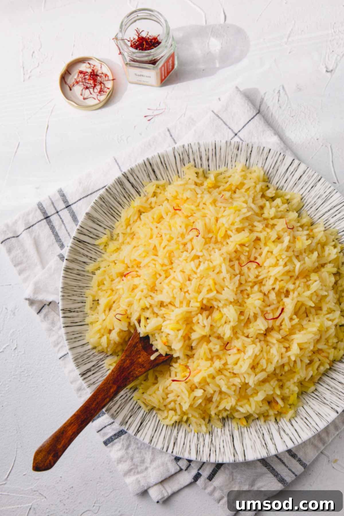 Fragrant Golden Pilaf 2 Beautifully plated saffron rice garnished with herbs and a wooden spoon, ready to be served.