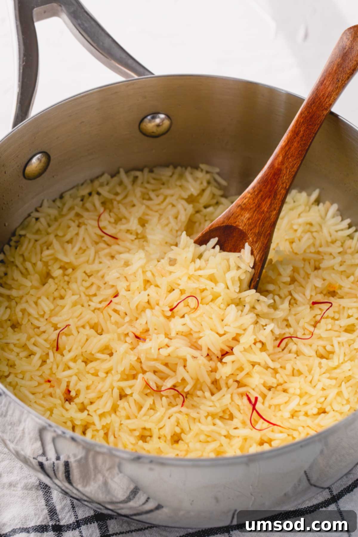 Fragrant Golden Pilaf 8 Cooked saffron rice in a non-stick skillet, freshly fluffed with a wooden spoon, ready to be served.