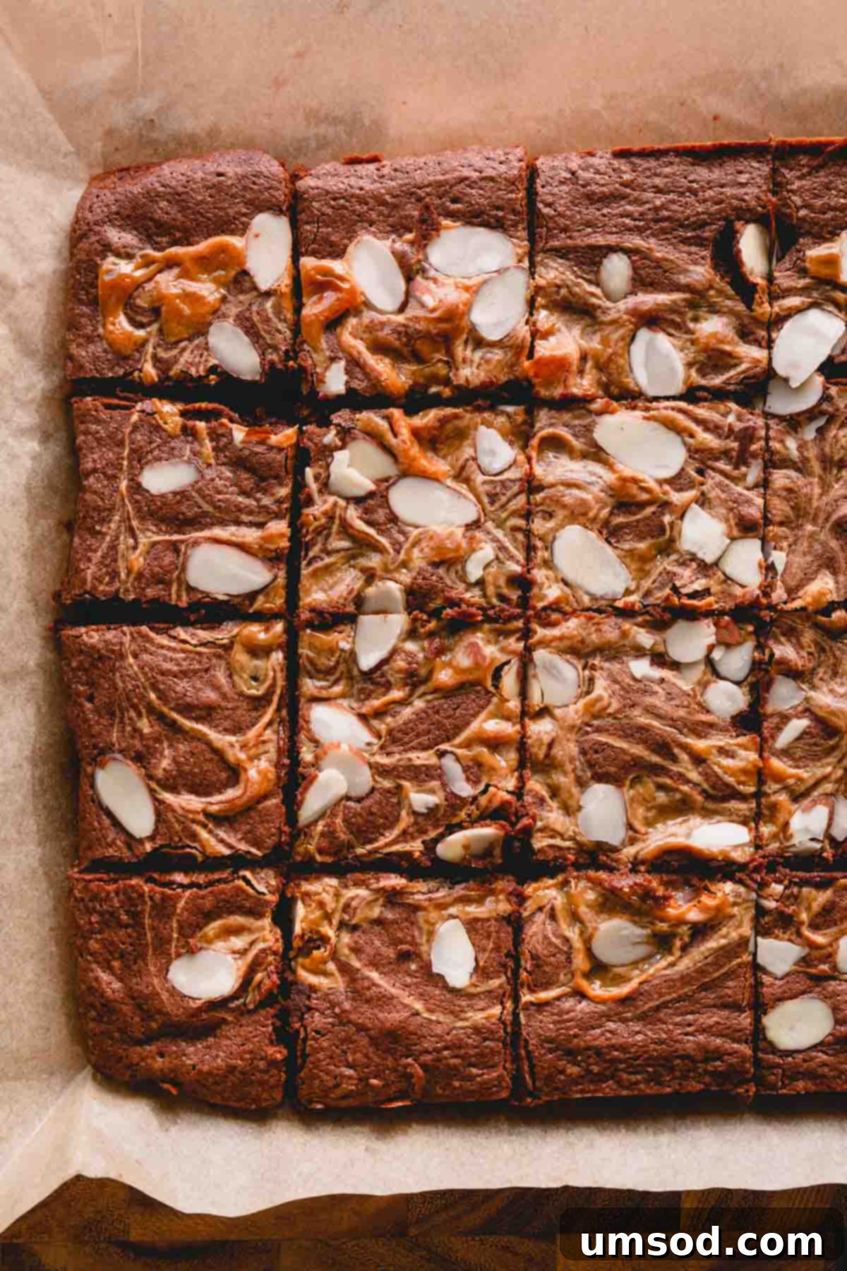 Dulce De Leche Swirled Almond Brownies 7 Baked brownies perfectly sliced into squares, presented on a sheet of brown parchment paper.
