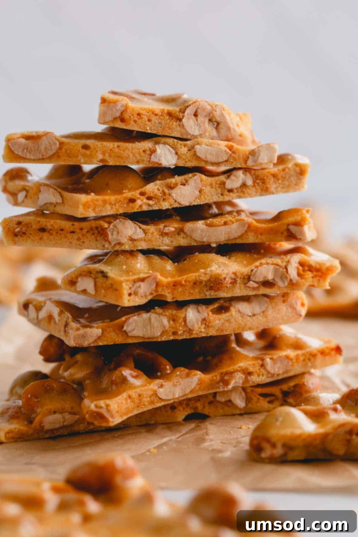 Effortless Microwave Peanut Brittle 2 A stack of golden-brown microwave peanut brittle pieces, showcasing their light and airy texture.