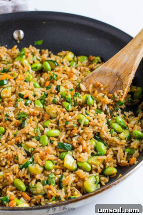 Wok-Tossed Veggie Rice 3 Close-up of freshly cooked Sweet Potato Vegetable Fried Rice in a large skillet, highlighting the textures and bright colors of the ingredients during cooking.