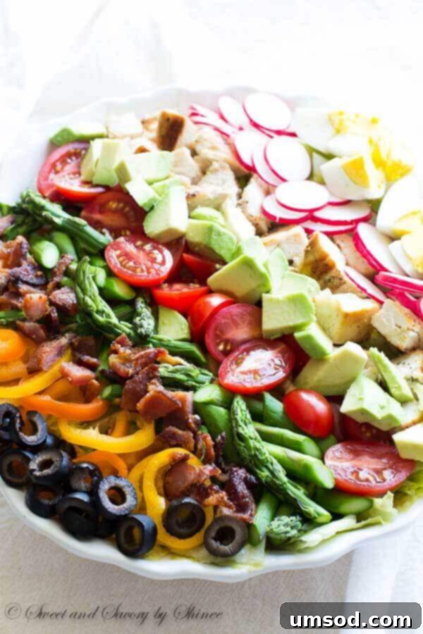 A vibrant, generously loaded Spring Cobb Salad featuring grilled chicken, crispy bacon, fresh asparagus, and the tangy Marzetti® Vineyard Dressing Balsamic Cabernet.