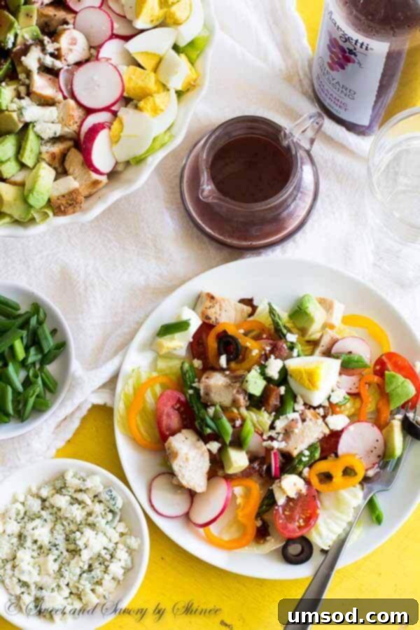 Serving a hearty Spring Cobb Salad with tongs, illustrating its abundant and satisfying portions, ready to be enjoyed.