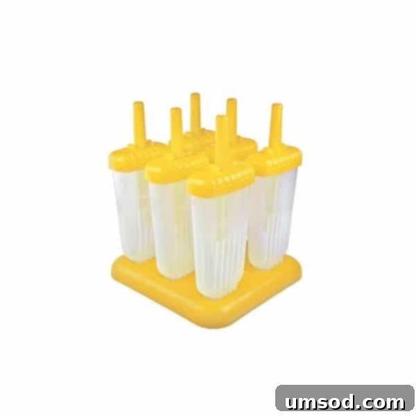 Close-up of a hand holding a popsicle mold, showing several perfectly formed pineapple popsicles.