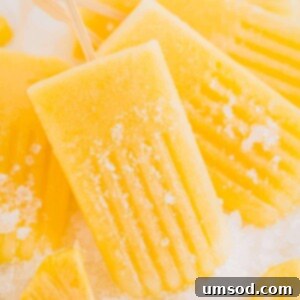 A stack of golden pineapple popsicles on a wooden board, ready to be enjoyed.