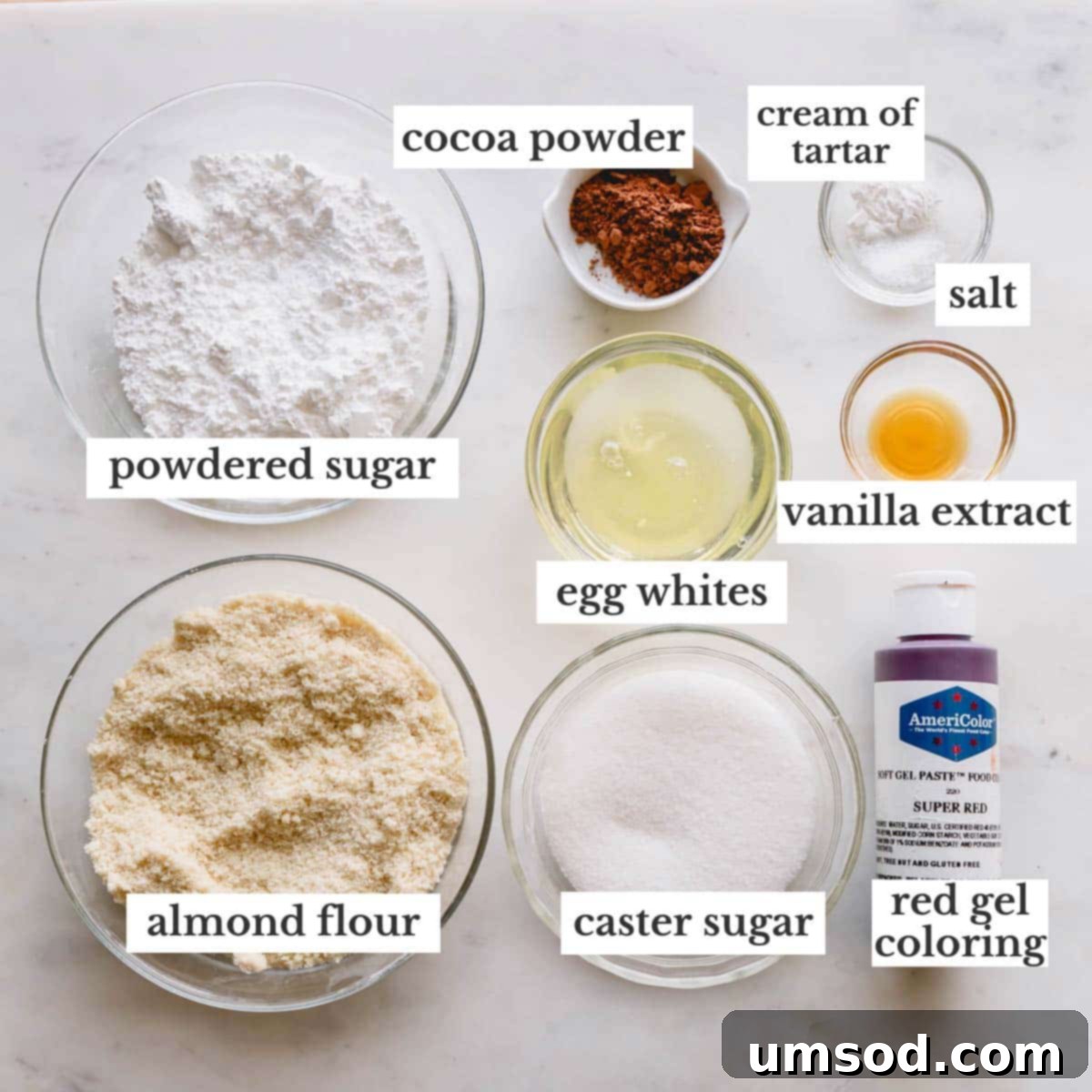 Assortment of fresh red velvet macaron ingredients, including egg whites, almond flour, powdered sugar, and cocoa powder, meticulously arranged in individual bowls.