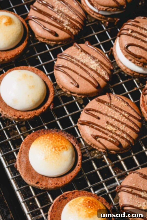 Another view of a chocolate macaron shell on a wire rack with a dollop of marshmallow filling, ready for assembly.
