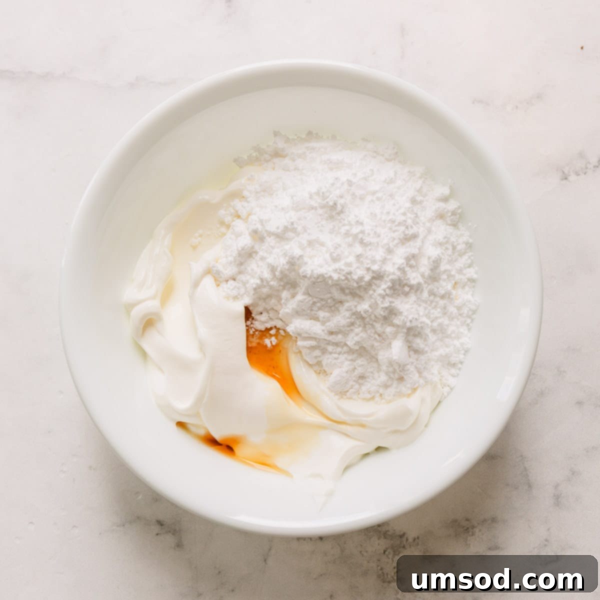 Fudgy Chocolate Zucchini Sheet Cake 7 Ingredients for sour cream frosting – sour cream, powdered sugar, and vanilla – in a bowl, ready to be mixed.