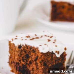 A square slice of double chocolate zucchini cake with a bite missing, showcasing its rich texture and chocolate chips.