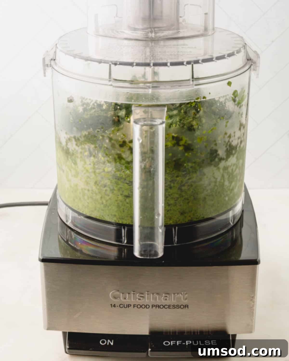 Big Batch Basil Pesto Recipe 10 Basil pesto processing into a vibrant green mixture in a food processor.