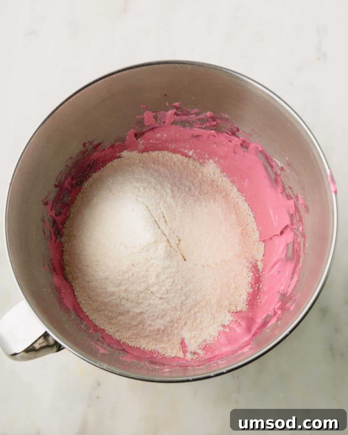 Cranberry Citrus Macarons 11 Almond flour being sifted into a bowl of cranberry macaron batter.