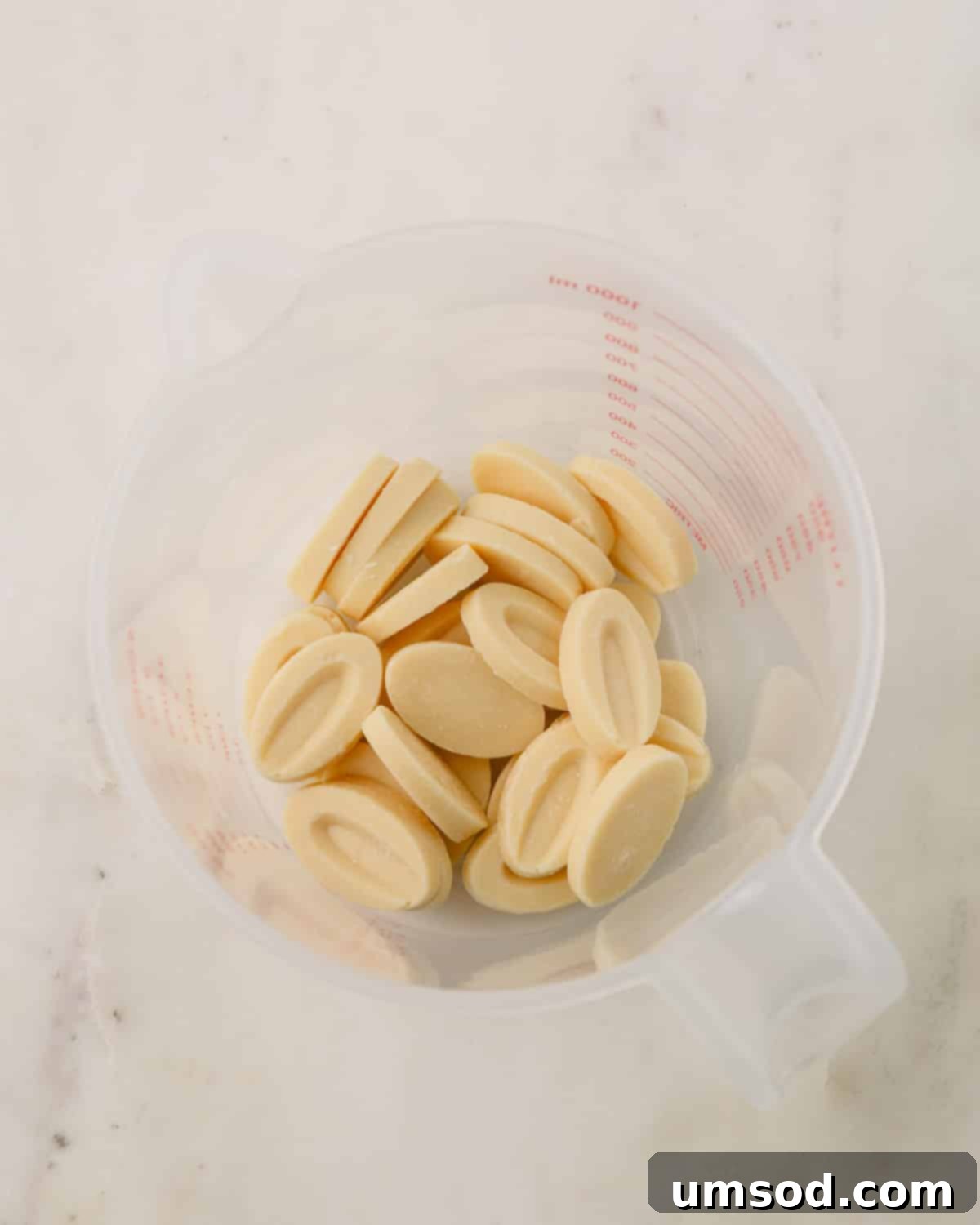 Cranberry Citrus Macarons 22 White chocolate melting wafers in a clear plastic measuring cup.