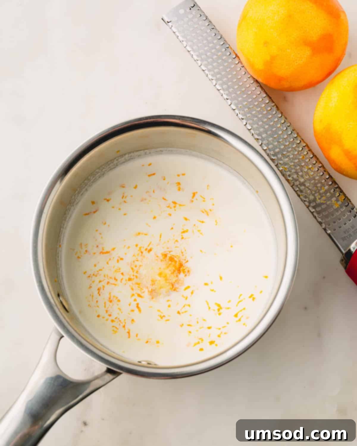 Cranberry Citrus Macarons 23 A pot of melted orange chocolate infused with fresh orange zest, alongside a zester and fresh oranges.