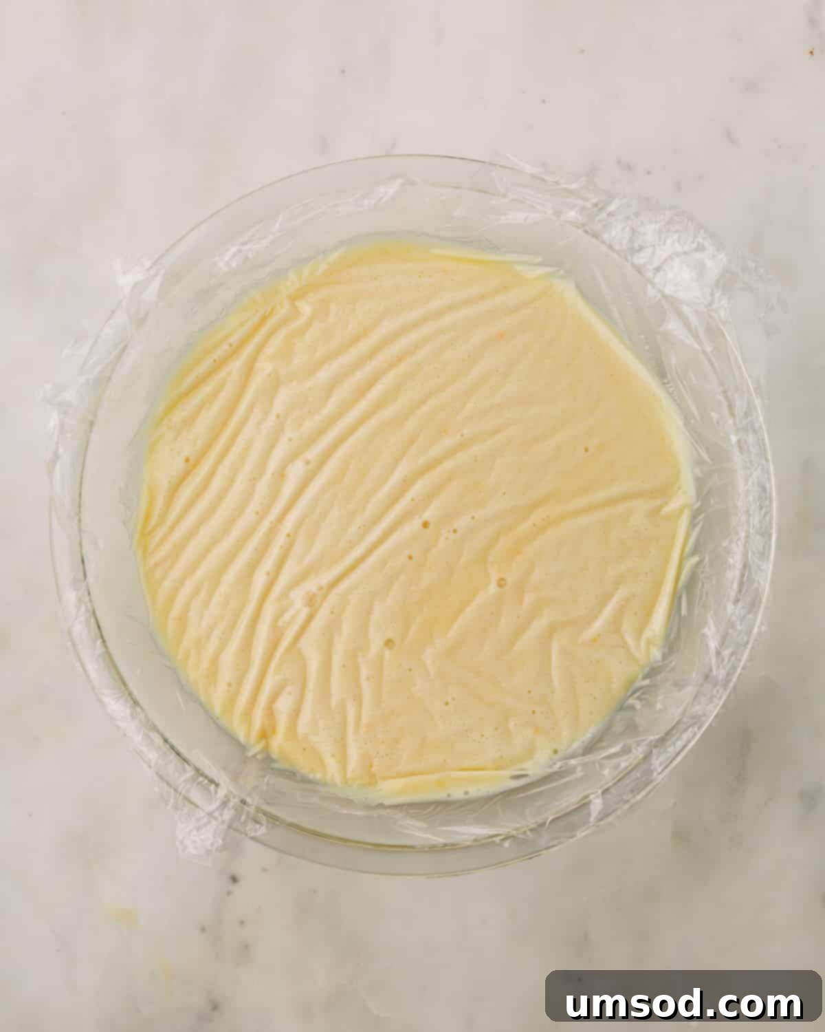 Cranberry Citrus Macarons 24 A bowl of white chocolate orange ganache, covered with plastic wrap to prevent skin formation.