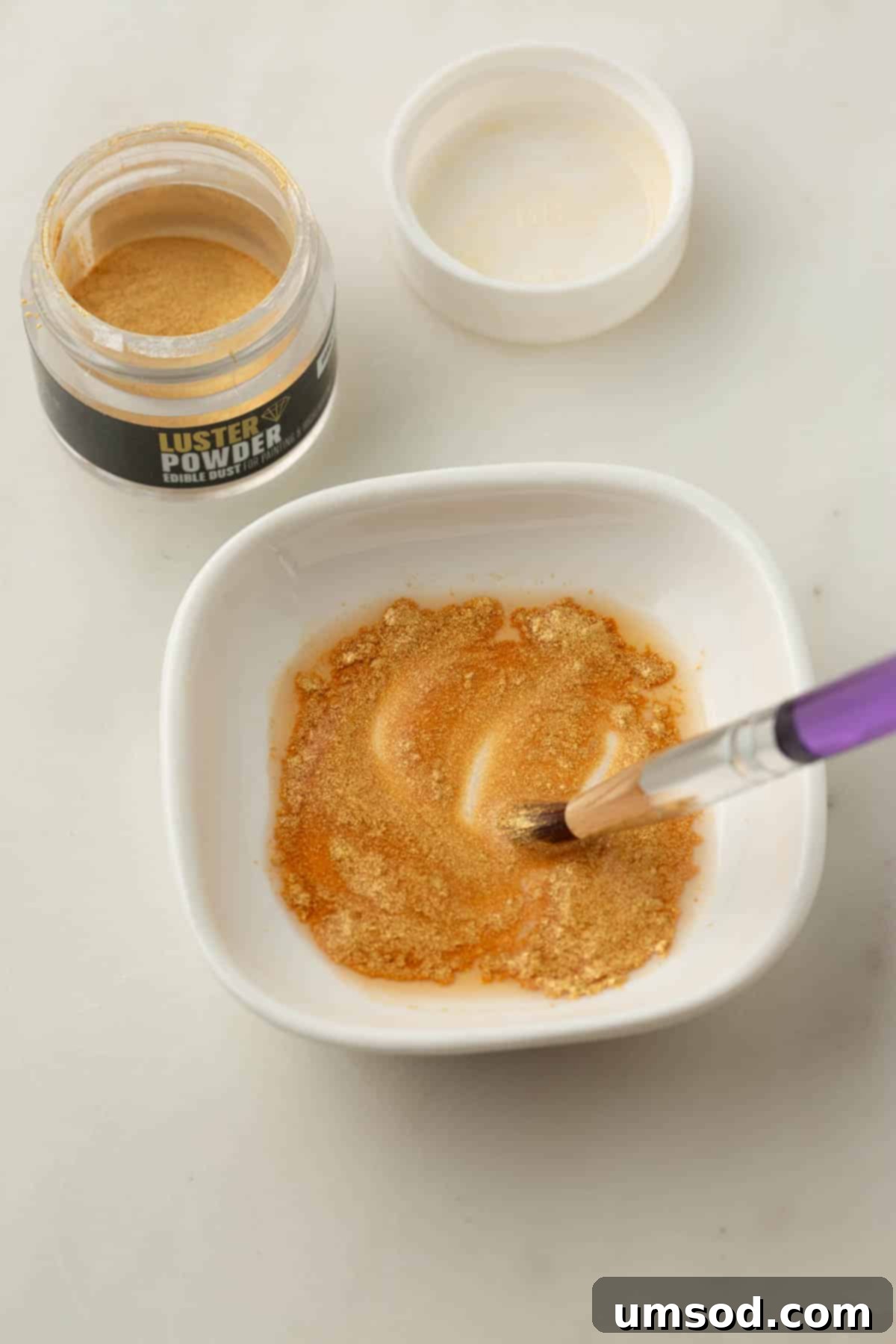 Cranberry Citrus Macarons 28 A bowl of shimmering edible gold powder, with a fine paint brush ready to apply it to the macarons.