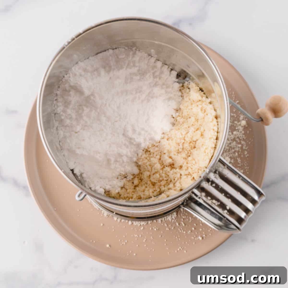 Cranberry Citrus Macarons 5 Powdered sugar and almond flour inside of a hand-crank sifter.